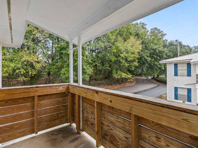 Private covered balcony overlooking wooded grounds at Oak Hollow Apartments