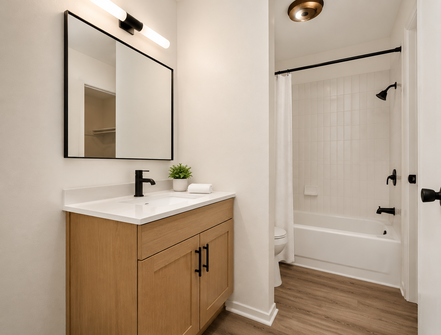 Rendering of a renovated bathroom at Oak Hollow — wood vanity, black fixtures, and tiled tub surround